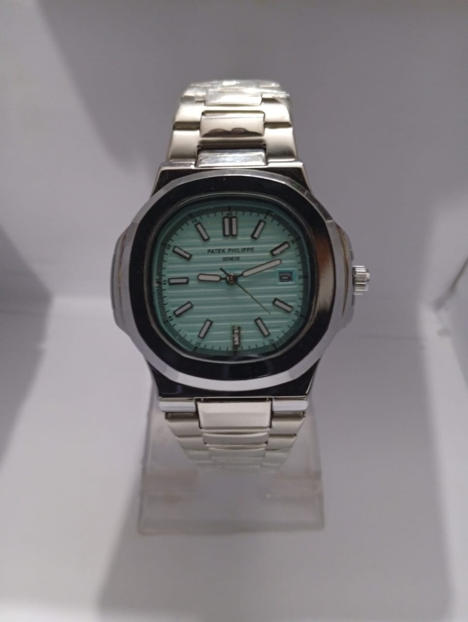 Silver watch with a green face on a white background