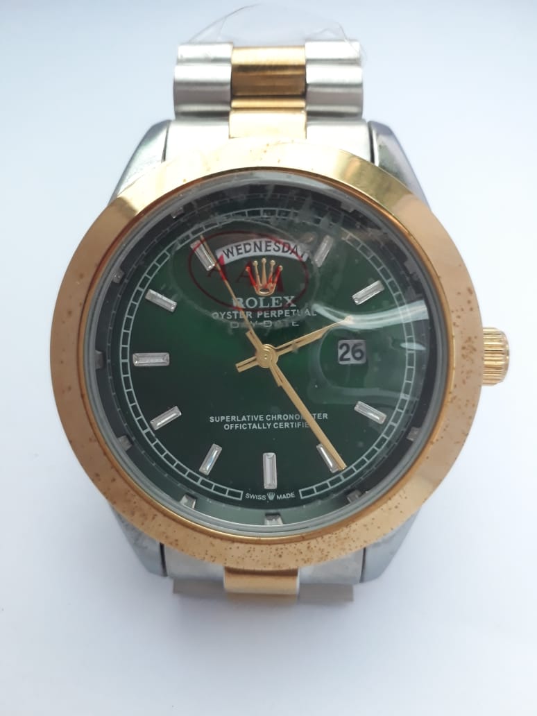 Rolex watch with green face and gold and silver case on a white background